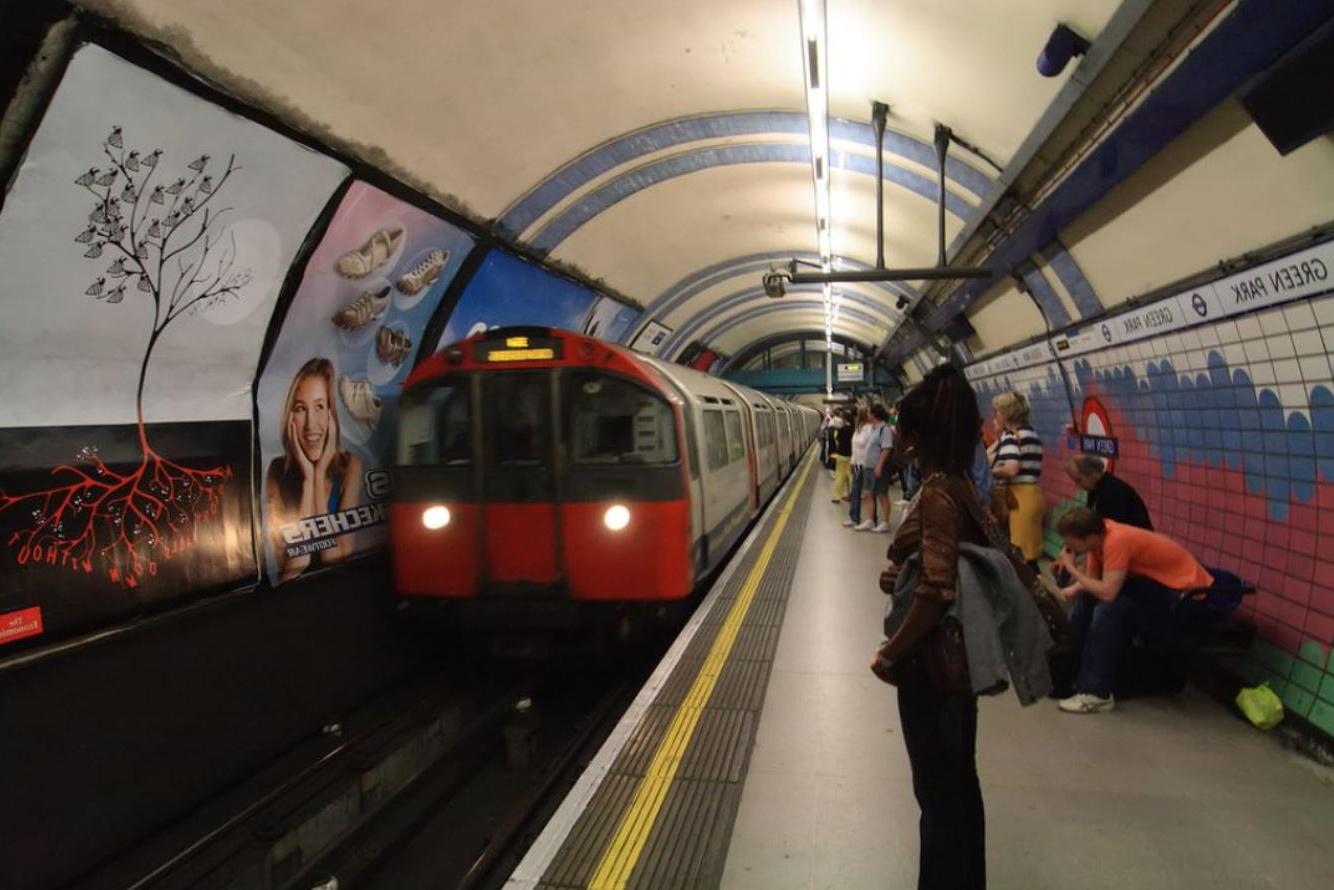 Woman standing on Green Park tube station platform as a tube passes by